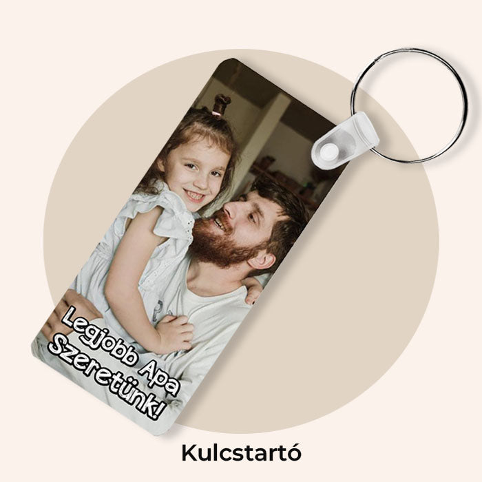 Egyedi fényképes kulcstartó apák napi ajándék a legjobb apa szeretünk felirattal, barna háttér előtt.